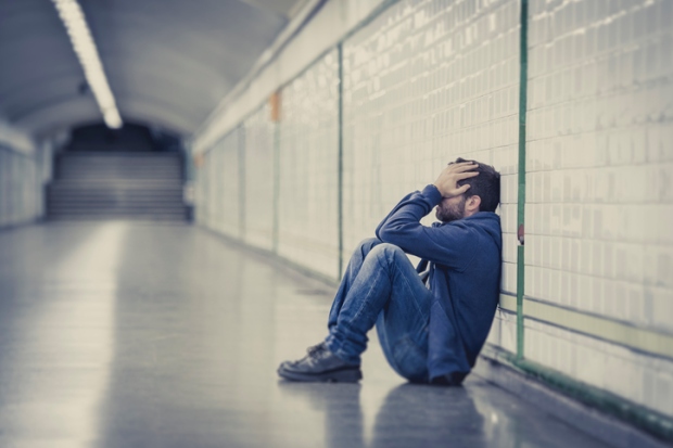 man lost in depression sitting on ground street subway tunnel